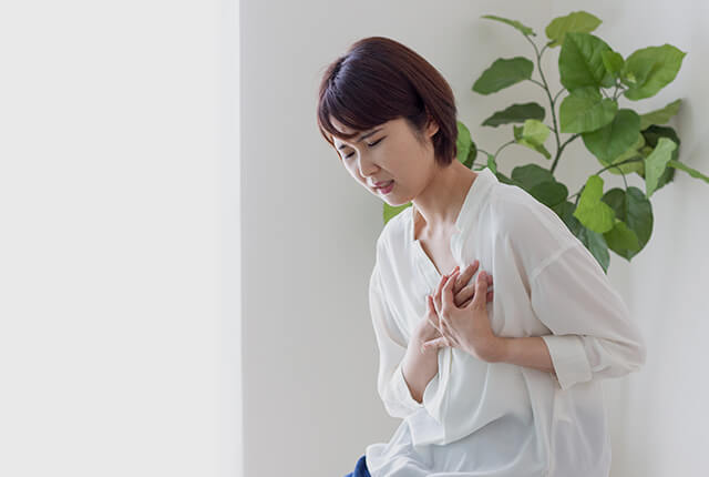 胸部に手を当て痛がっている女性